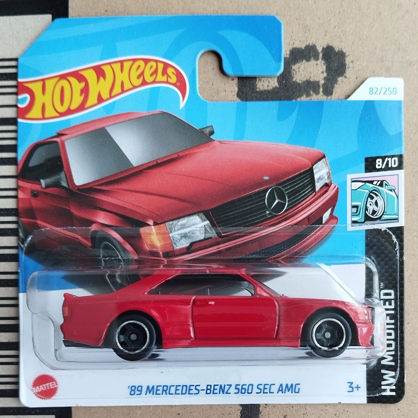 Hot Wheels 89 Mercedes-Benz 560 SEC AMG toy car in packaging on a cardboard background