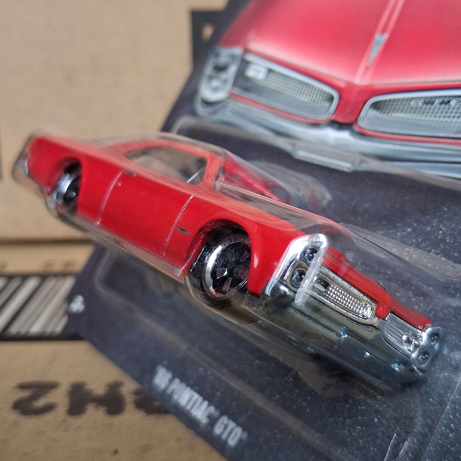 Side angle view of Hot Wheels 1966 Pontiac GTO red diecast car in blister, 1:64 scale