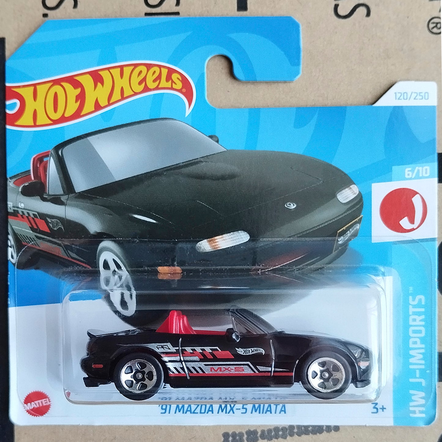 Hot Wheels toy car package featuring a black Mazda MX-5 Miata die-cast model with red and white racing decals, shown in its original blister card packaging.