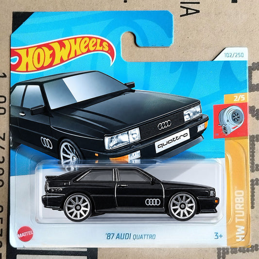 A Hot Wheels Mattel '87 Audi Quattro die-cast toy car in its original blister card packaging, featuring a black car model with silver wheels on a blue and orange card.