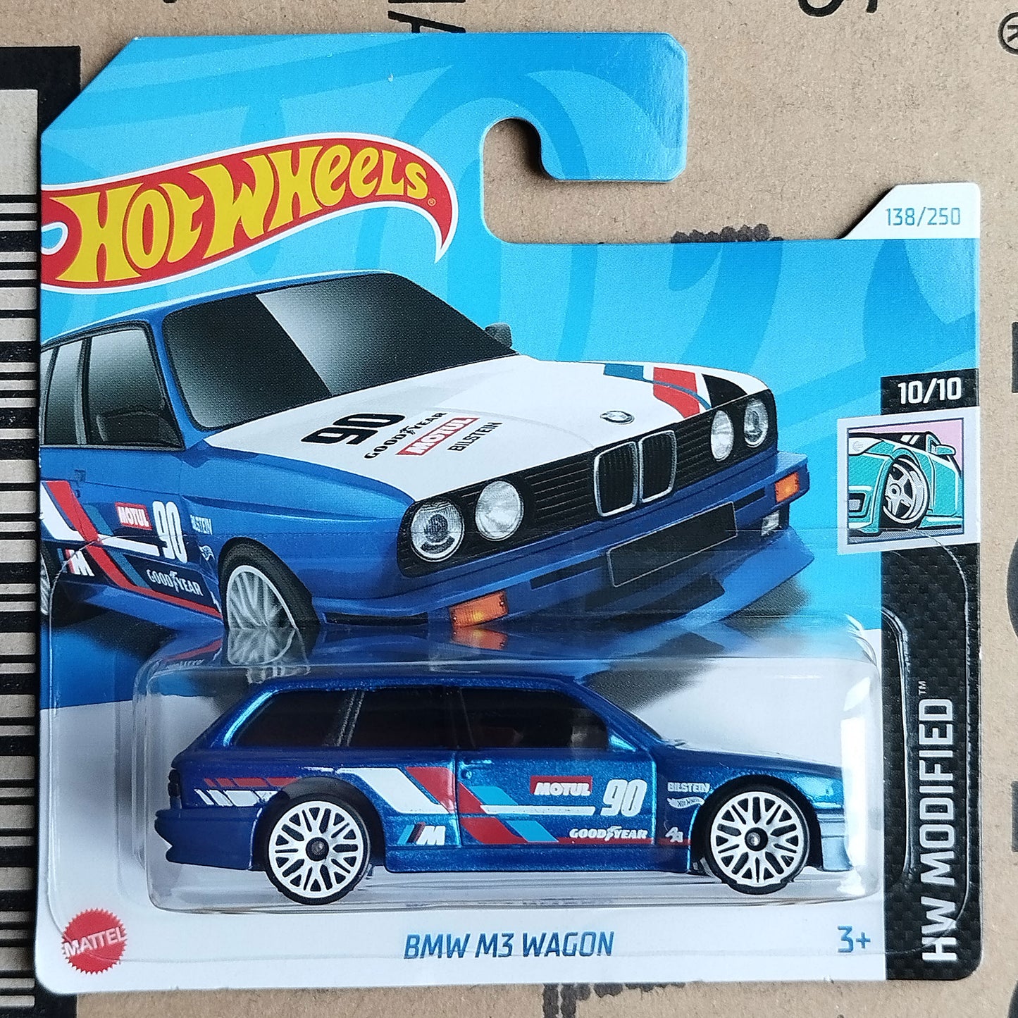 Hot Wheels die-cast toy car of a BMW M3 Wagon in a blue, white, and red racing livery, presented in its original blister card packaging.