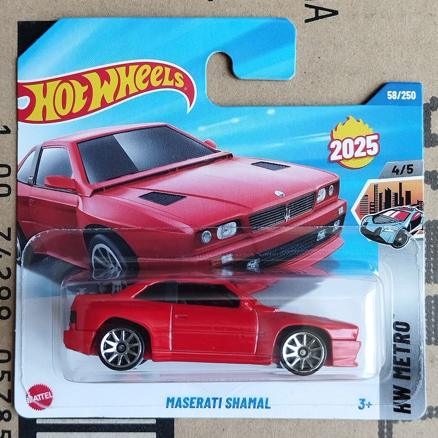 A Hot Wheels Mattel die-cast toy car of the Maserati Shamal, model HW Metro 2025. The red toy car is displayed in its original blister pack on a blue and white card featuring the Hot Wheels logo and model details.