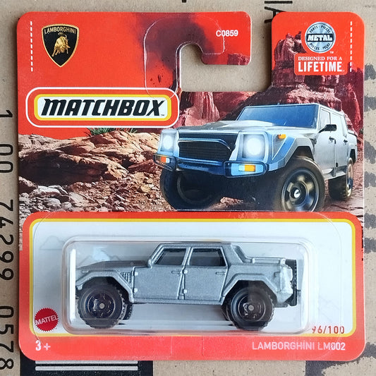 Matchbox Mattel Lamborghini LM002 die-cast toy car in its original red blister card packaging, featuring a silver-gray vehicle and a desert-themed background.